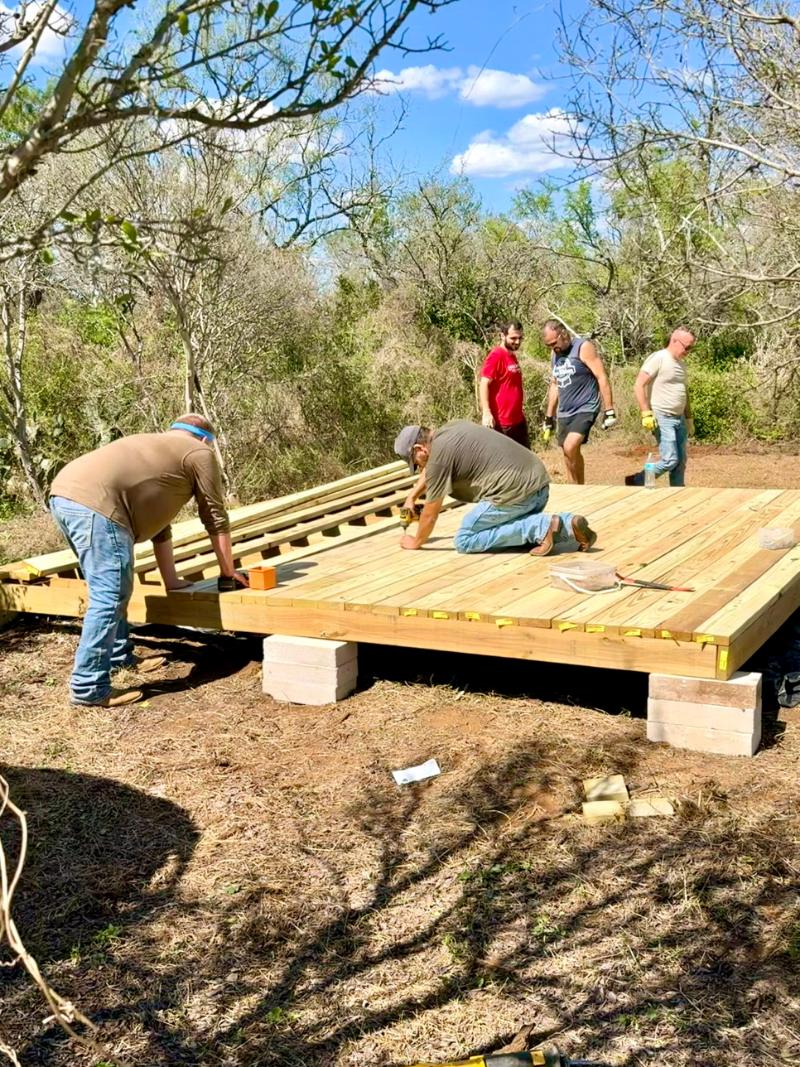 Volunteers screwing down decking on a new yurt platform