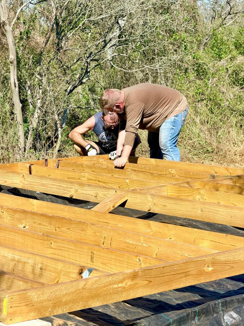 Two volunteers squaring up the frame of a yurt platform